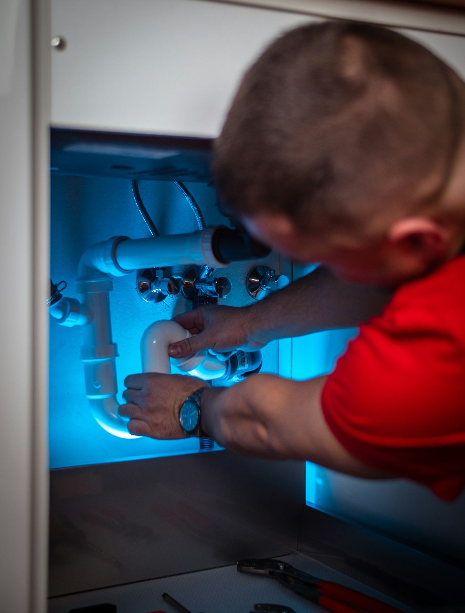 An installer fitting pipes under a sink